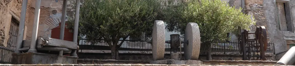 Una prensa y piedras de molino antiguas, expuestas al aire libre